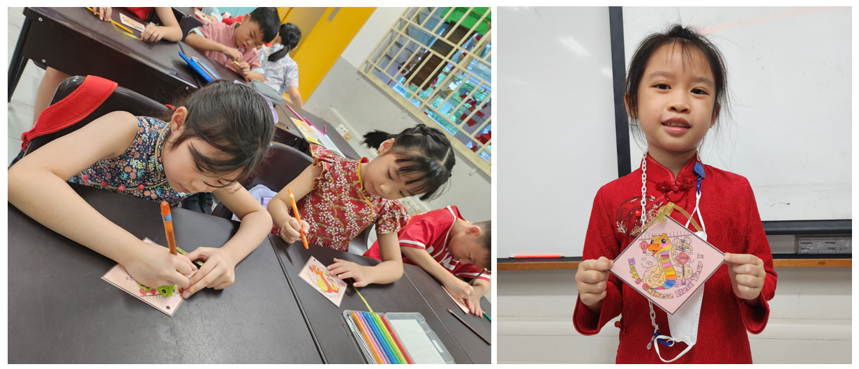 Children in traditional red outfits color craft cards at desks; one girl holds up her completed decorated card.