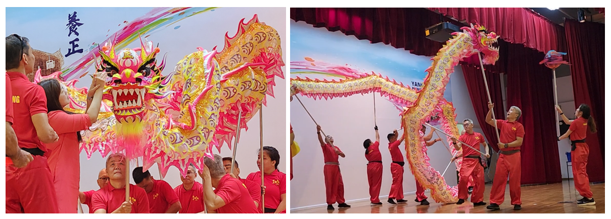 Performers in red uniforms perform a traditional Chinese dragon dance with a colorful yellow and pink dragon prop.
