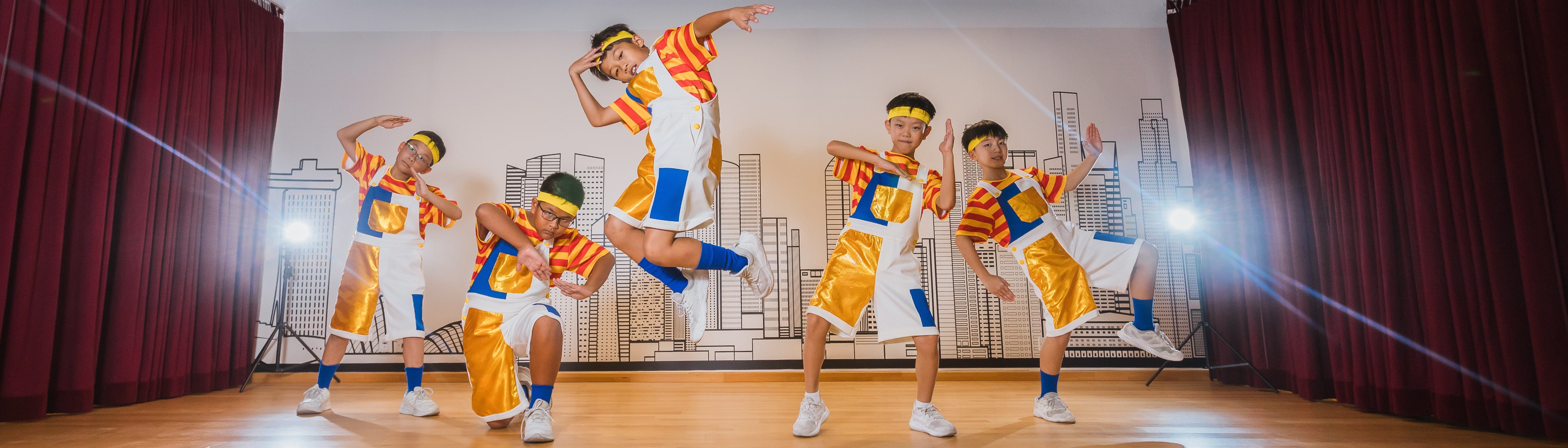 Four smiling boys in white ACS school uniforms with navy ties pose playfully against a white background.