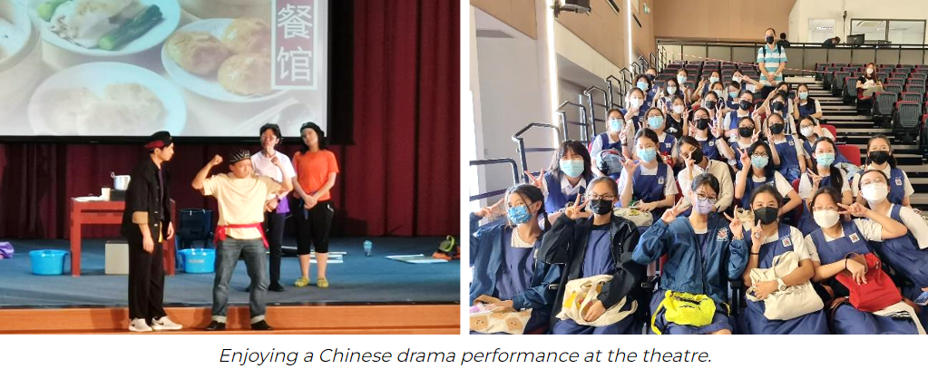 Students in masks pose in theatre seats while performers act on stage with a Chinese restaurant backdrop.