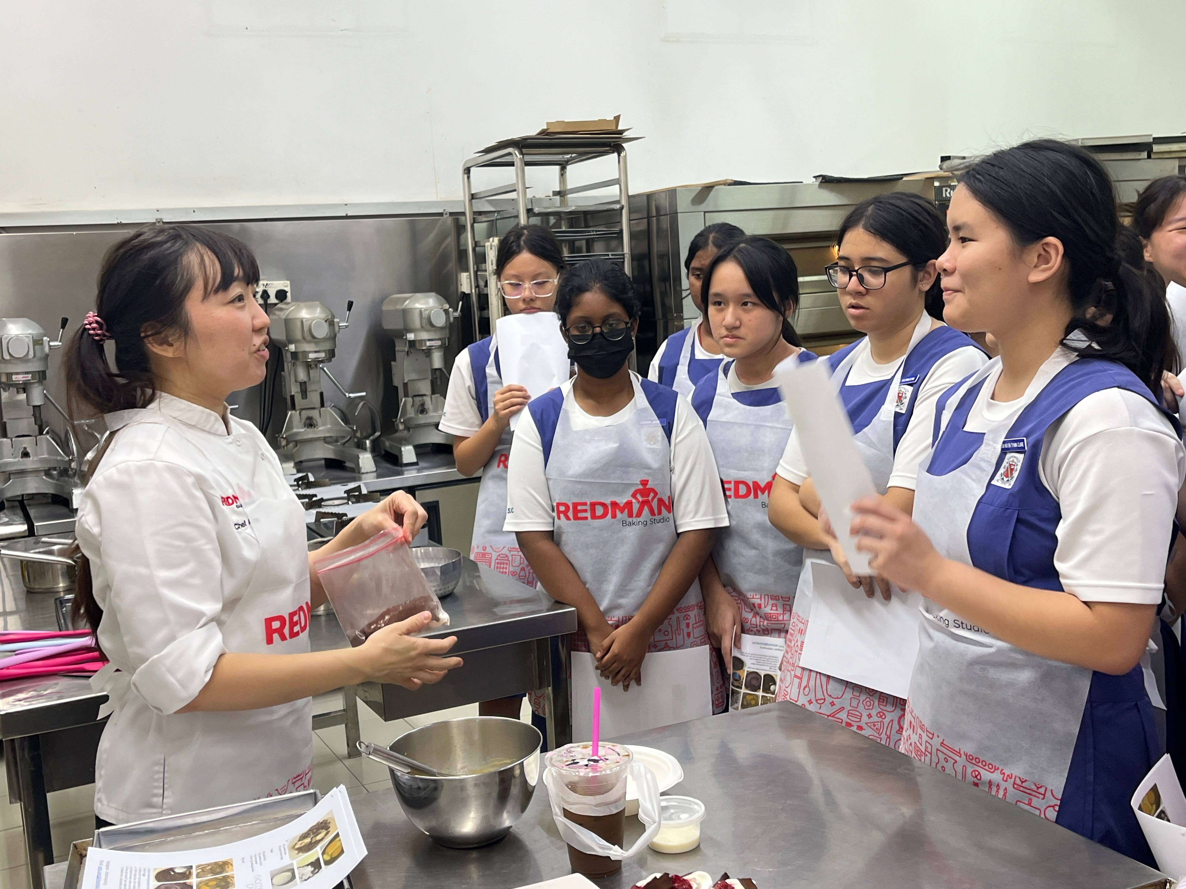 Students standing in a kitchen listening to the chef instructor