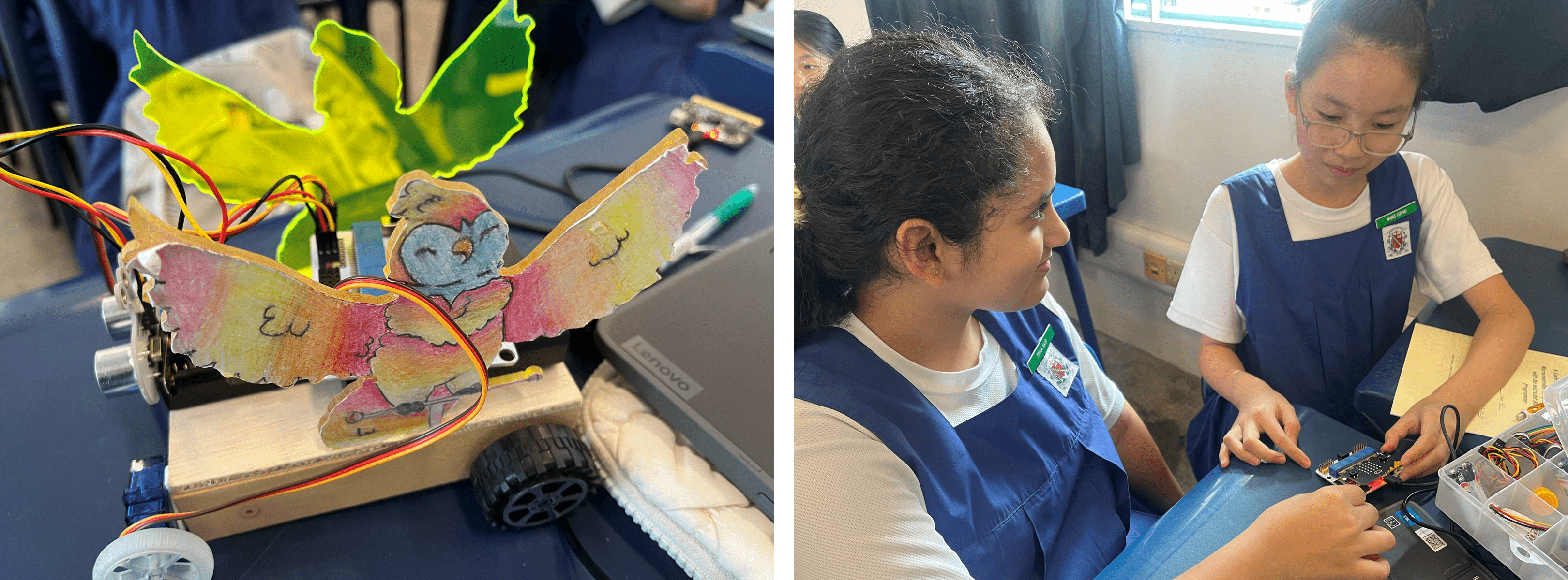 Two school girls in blue uniforms work on electronics; beside them is a colorful hand-drawn owl robot on wheels.