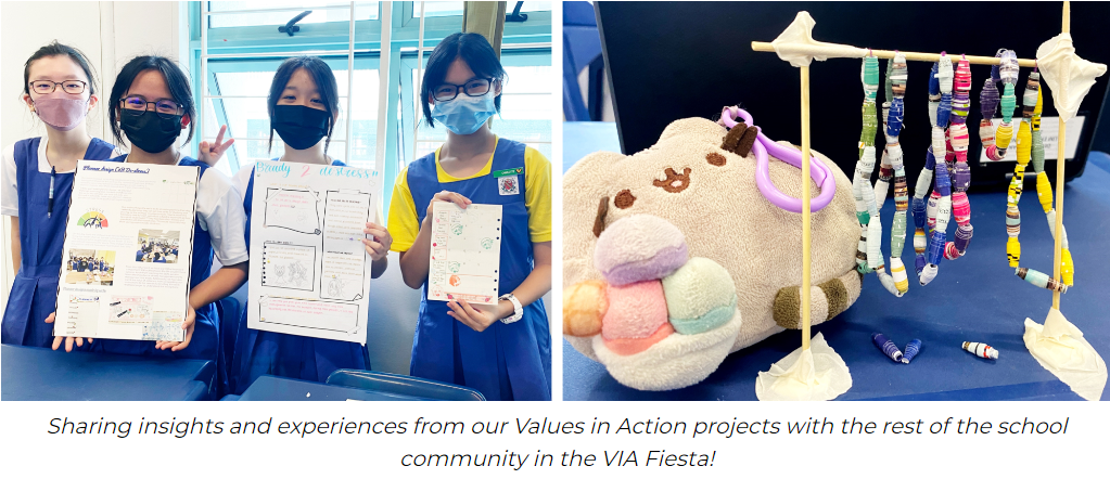 Four masked students hold project boards; beside them, a plush cat toy sits near a rack of colorful rolled paper beads.
