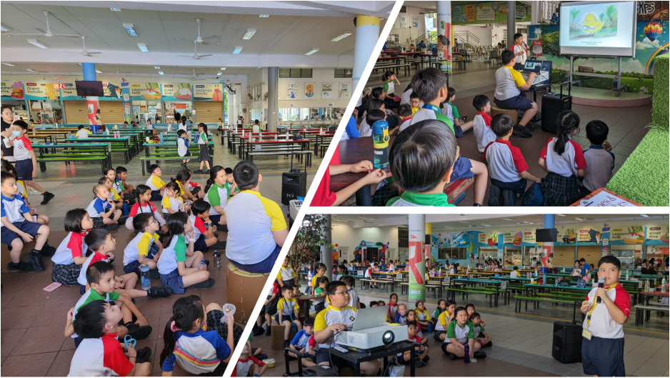 Young students in school uniforms sit on a canteen floor watching a presentation on a projected screen.