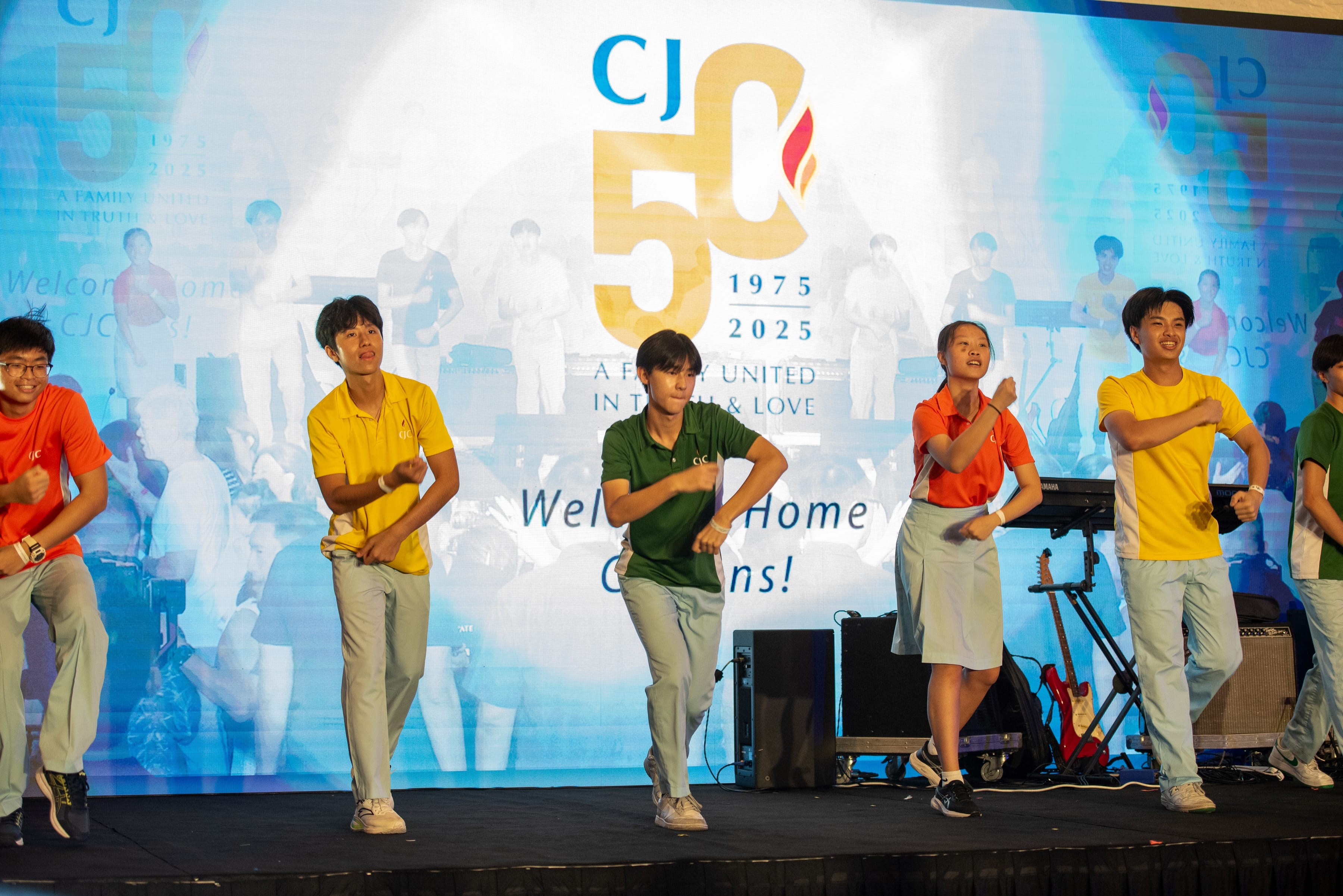Five dancers in colorful shirts perform on a stage before a CJ 50 anniversary backdrop.