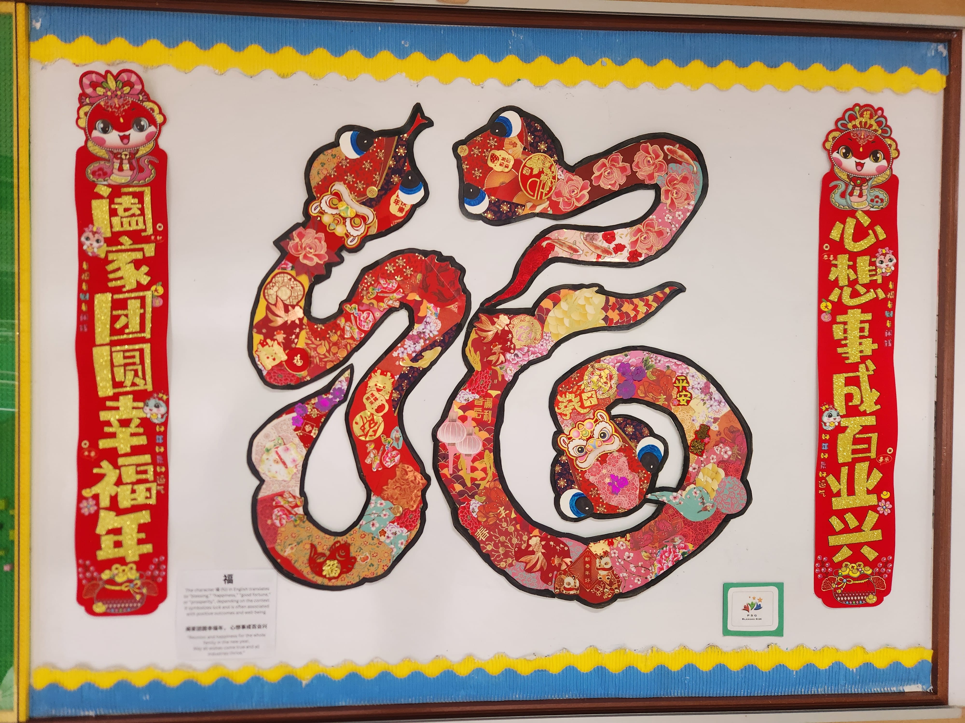 A colorful bulletin board displays the Chinese character Fu shaped like a snake, with red festive banners on each side.