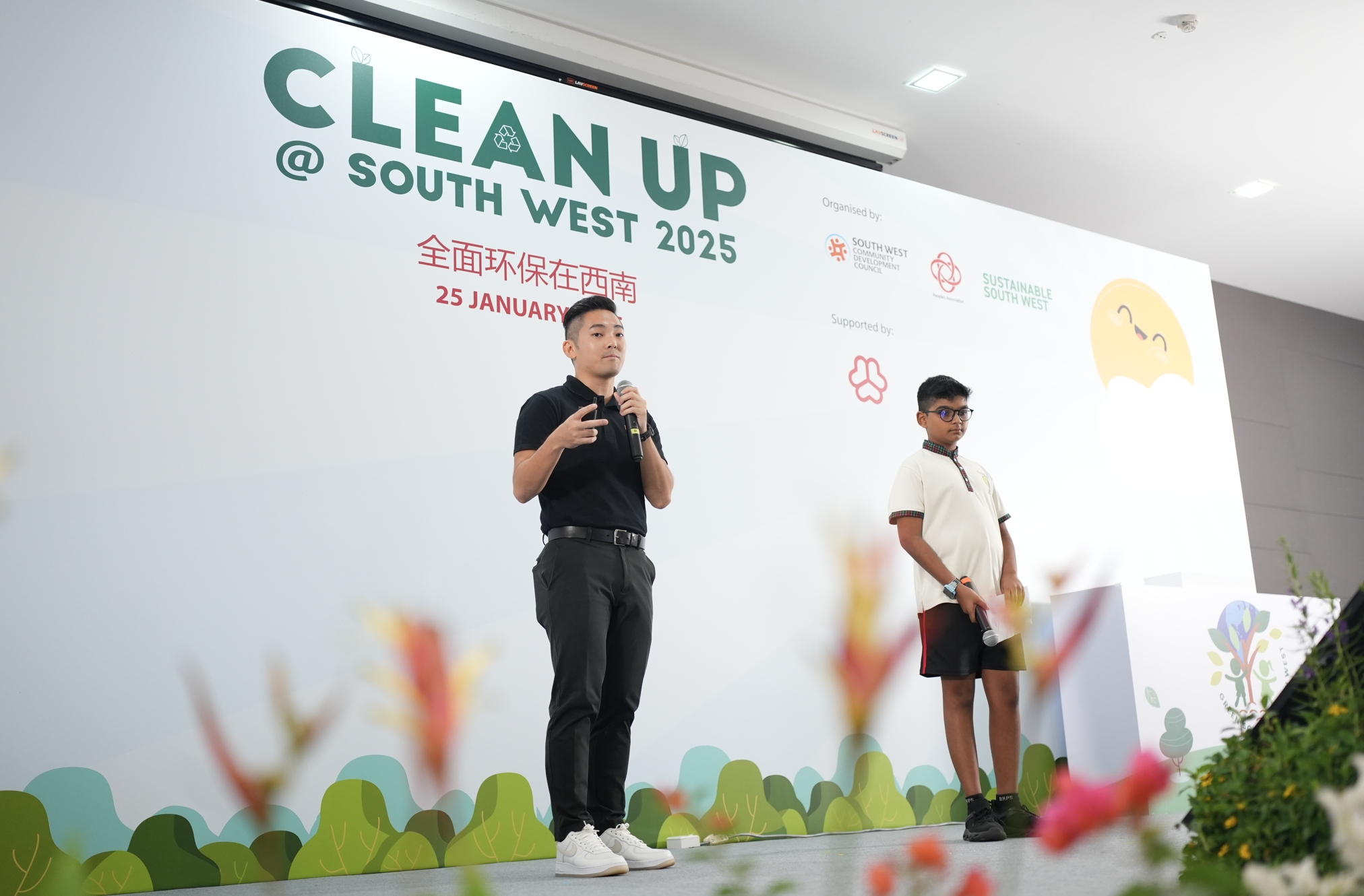 Two people stand on stage at the Clean Up at South West 2025 event on January 25, one holding a microphone.