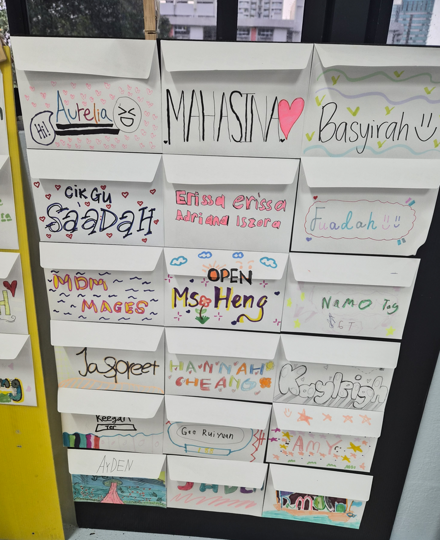 A wall of hand-decorated paper mailboxes labeled with colorful student and teacher names in a classroom.