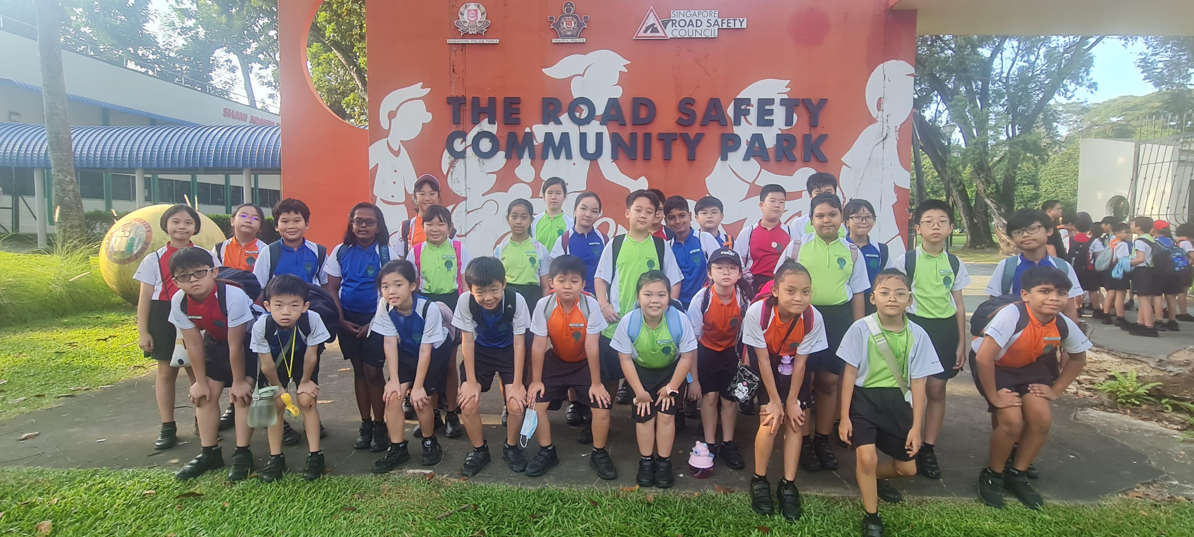 A group of schoolchildren posing in front of The Road Safety Community Park sign in Singapore.