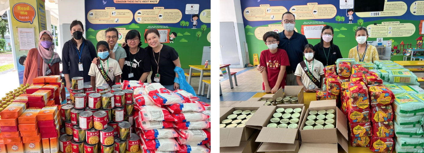 Groups of masked adults and children stand behind large collections of canned goods and packaged food in a school setting.