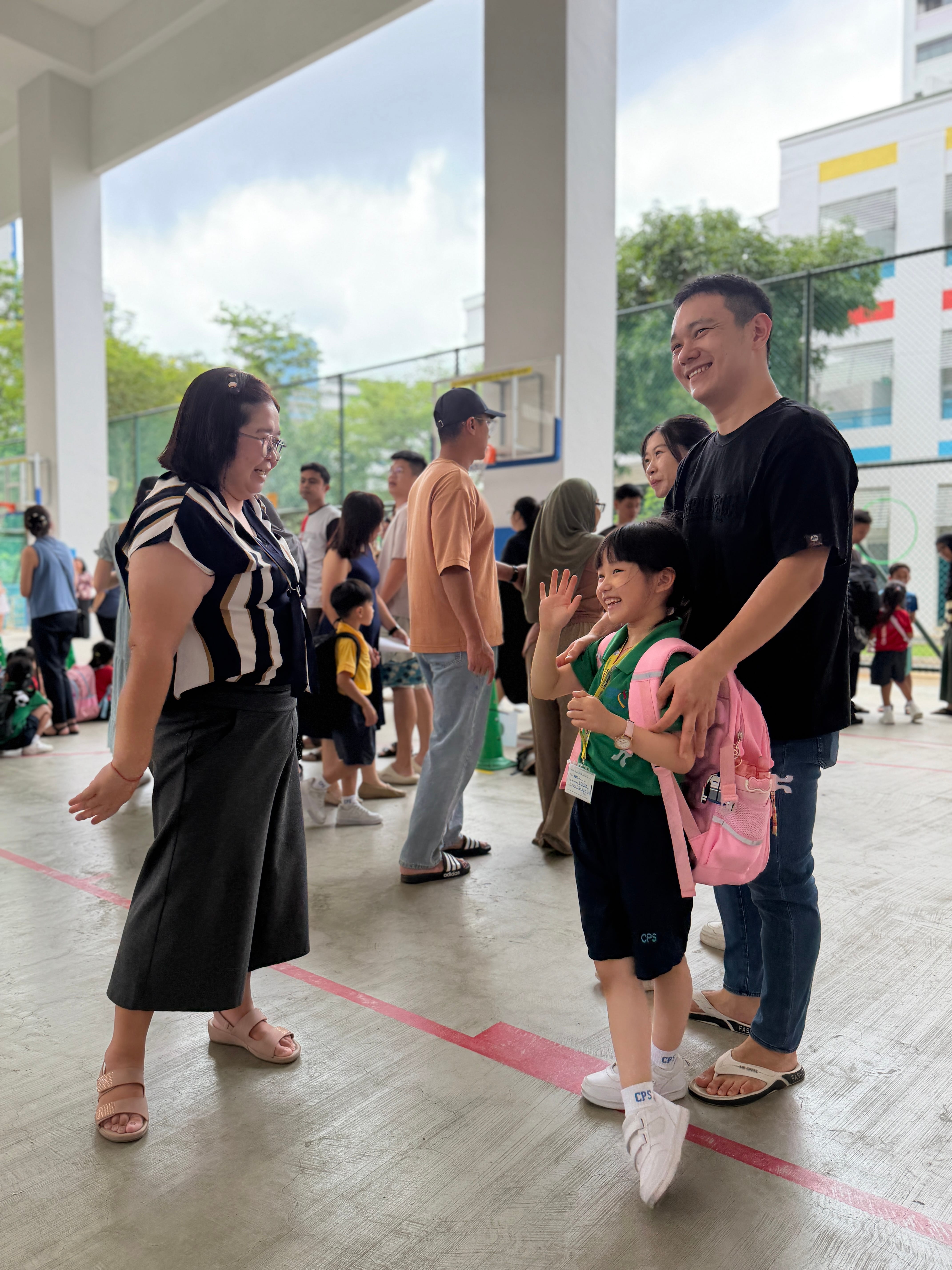 A teacher bids a cheerful farewell to a P1 student and parent during dismissal on the first day of school, reflecting the warm and reassuring environment created by the "To CPS We Go" programme. 
