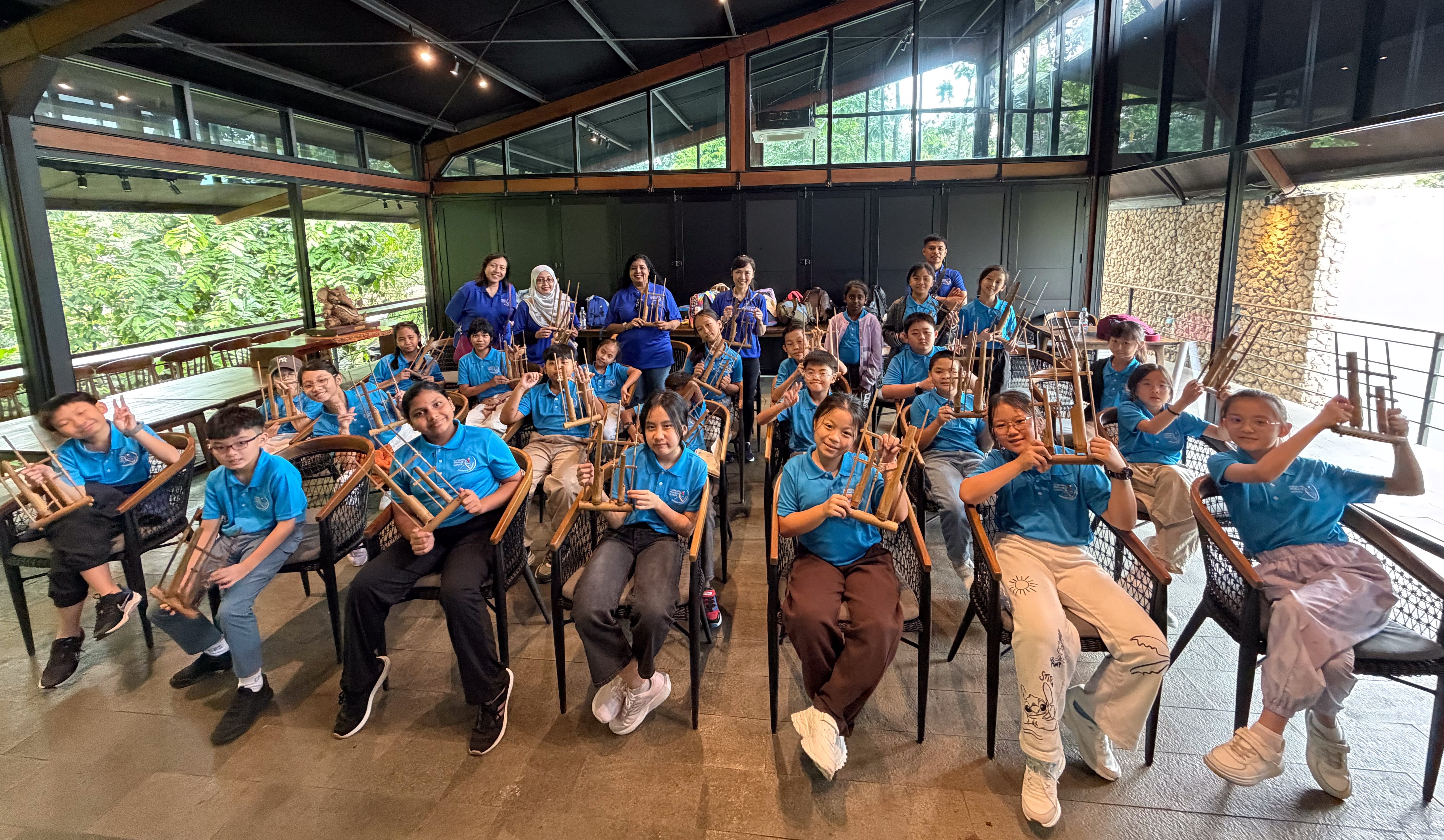 Students and teachers learning to play the angklung, a traditional Indonesian musical instrument, at Godong Ijo. 