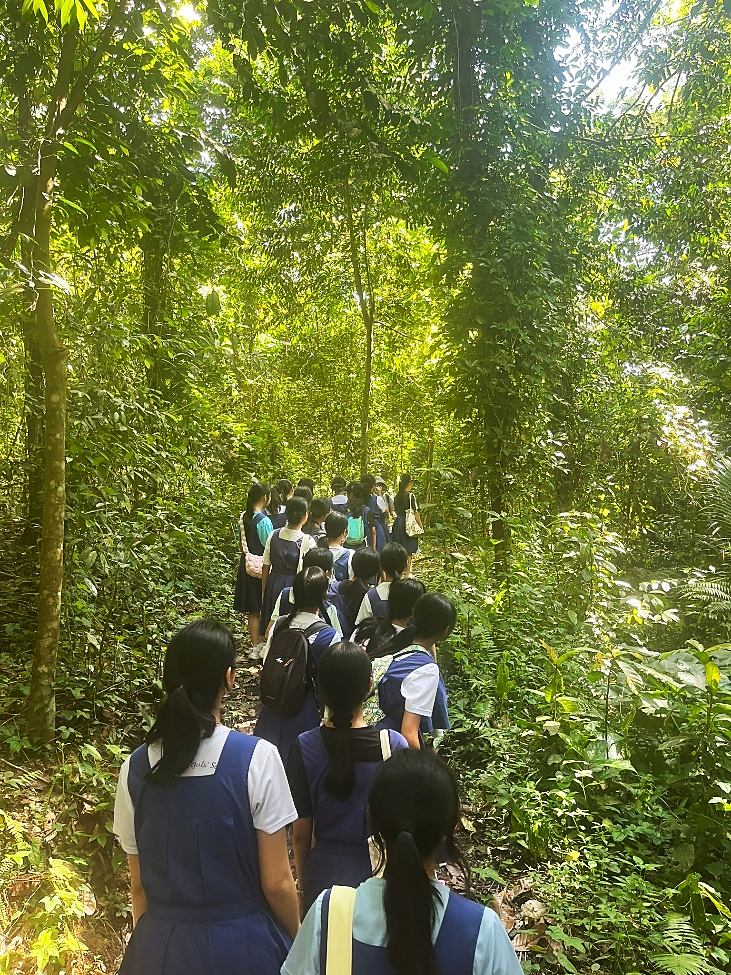 Green Club students walking along forested nature trail path.
