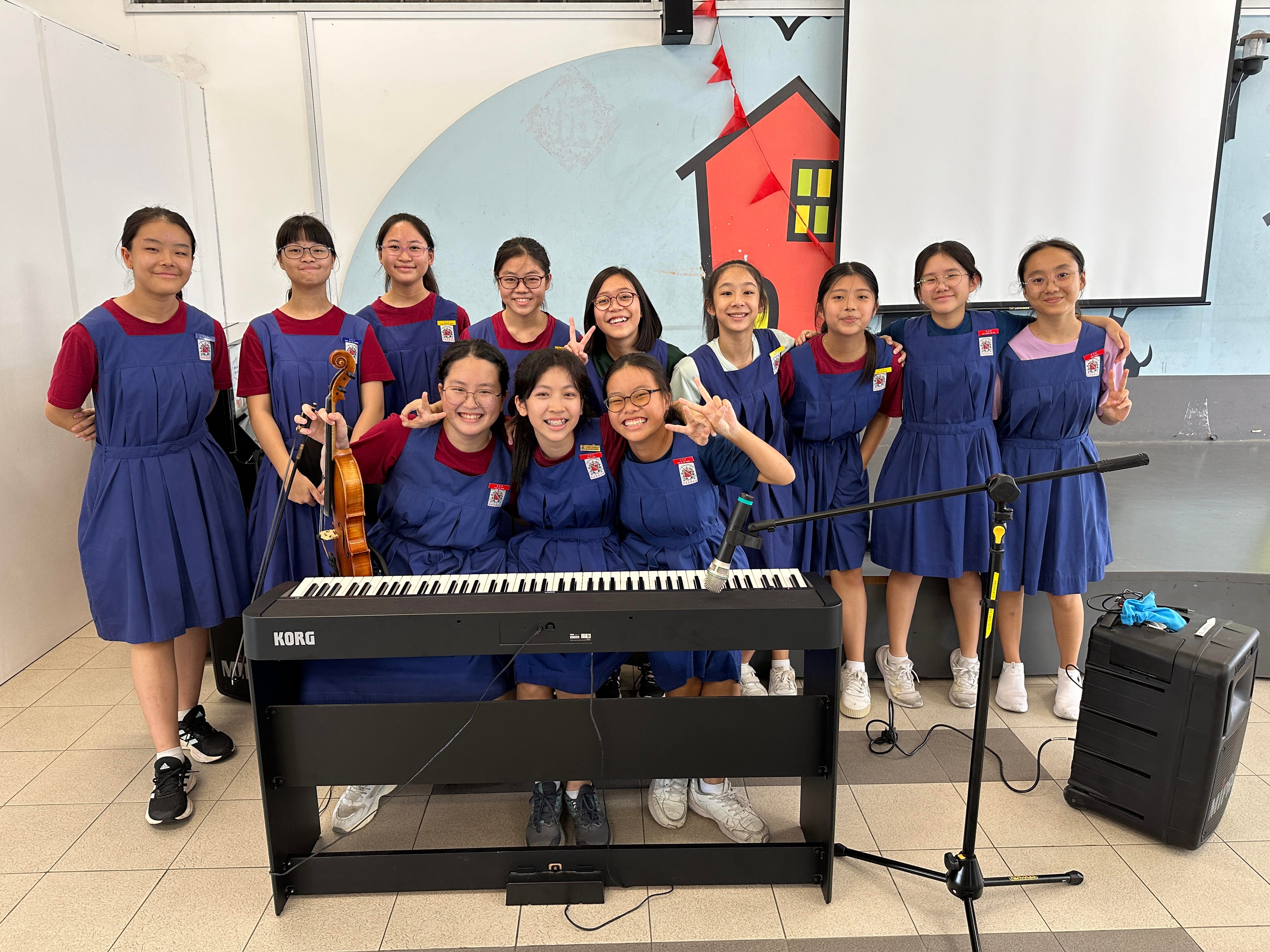 Music students smiling together behind a keyboard with a violin.