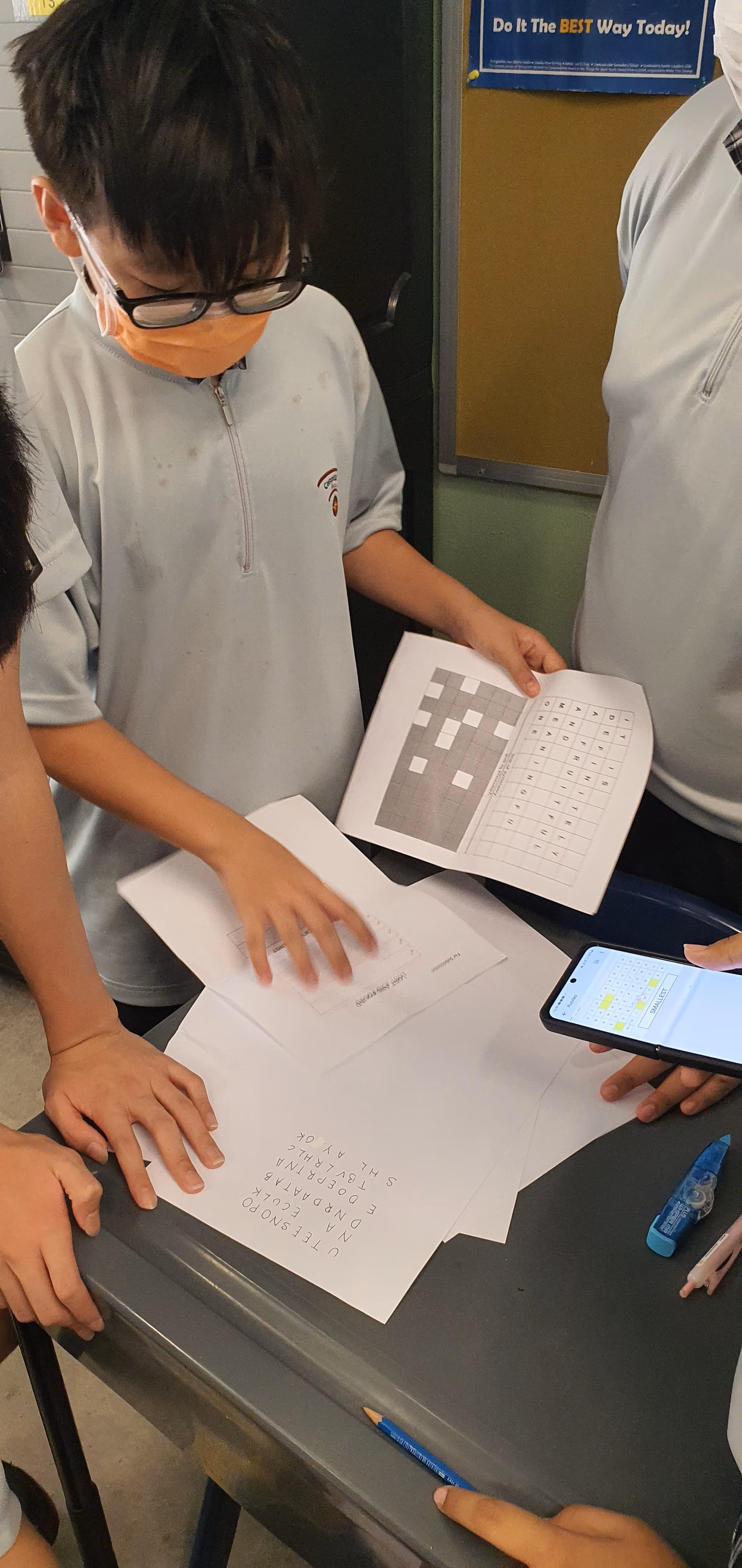 Students wearing masks gather around a humanoid robot with a screen at the TP-HRG Robotics Innovation Centre.