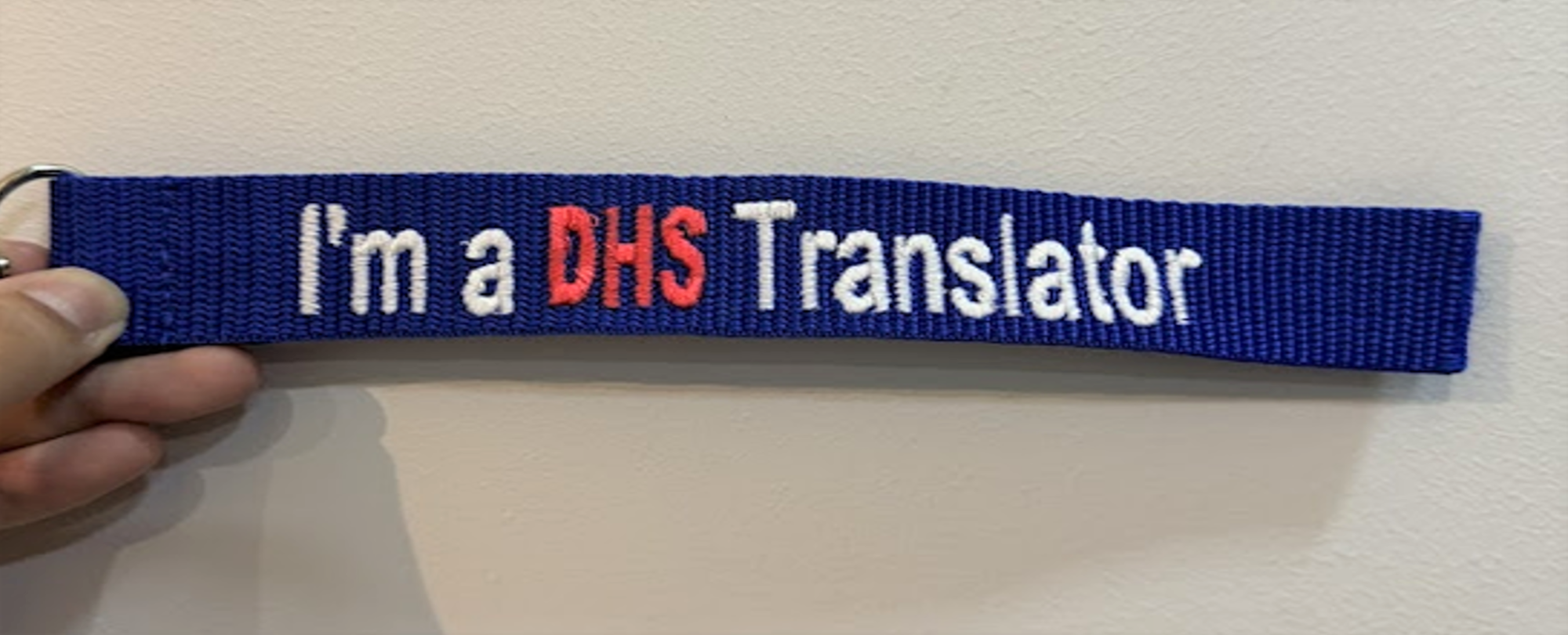A blue embroidered lanyard strap reading "I'm a DHS Translator" with "DHS" in red letters.