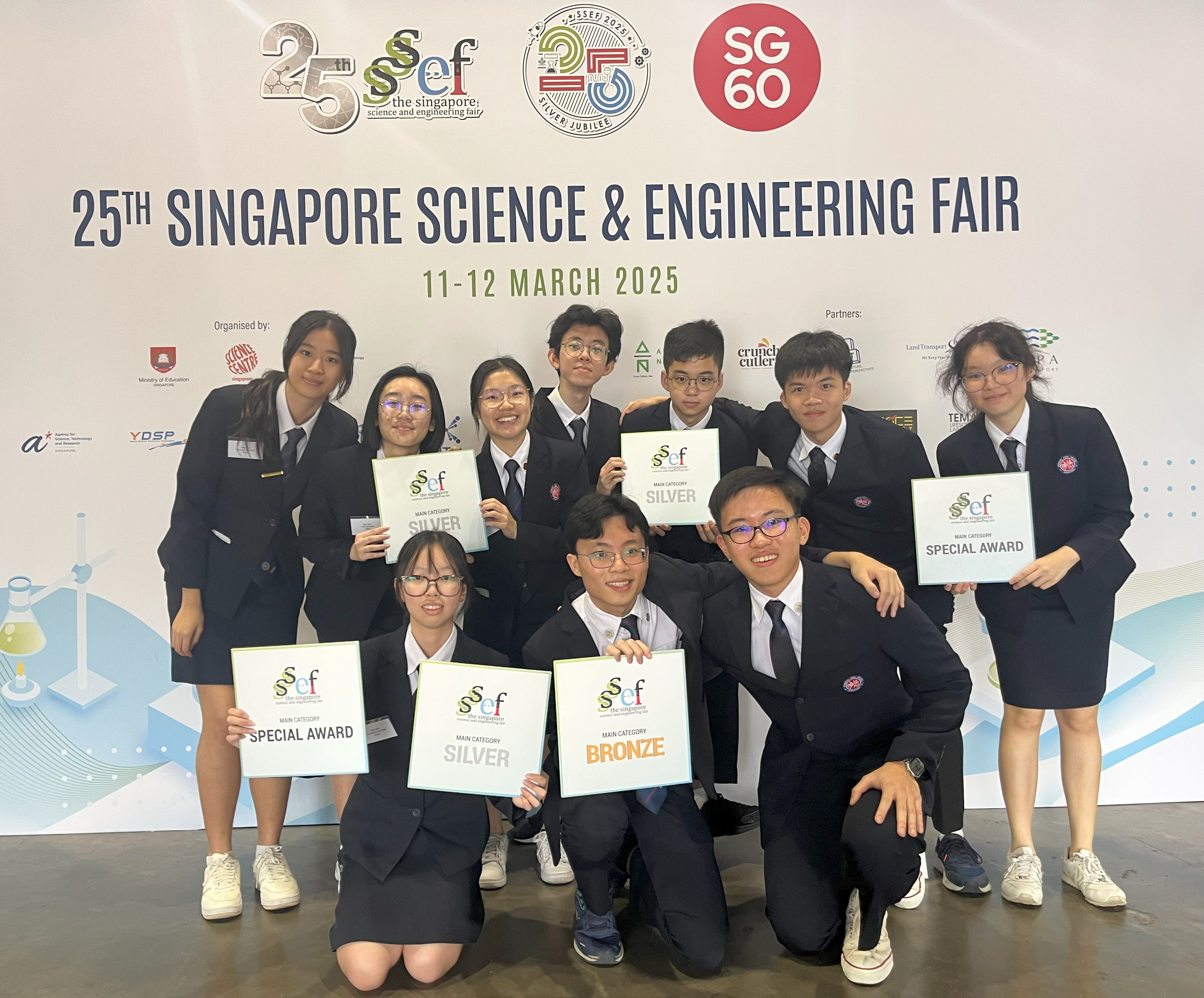 Ten students in school uniforms pose with Silver, Bronze, and Special Award certificates at the 25th Singapore Science and Engineering Fair.