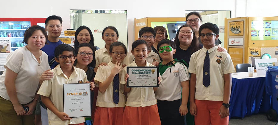 Group of students and adults posing with awards from the Ginnovation Challenge 2019 at an indoor event.