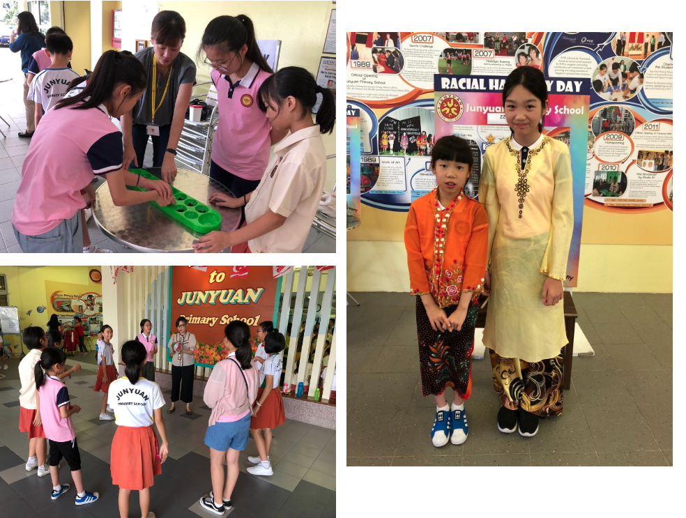 Two girls in traditional dress pose at a Racial Harmony Day display at Junyuan Primary School.