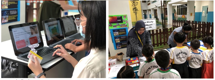 A masked student works on a laptop while children in uniforms gather around a teacher at an outdoor school booth.