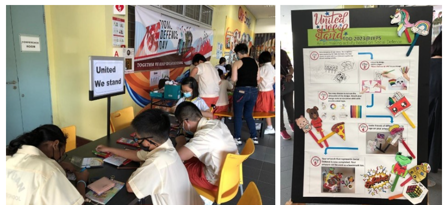 Students participate in a Total Defence Day activity called United We Stand, with a colorful display board nearby.