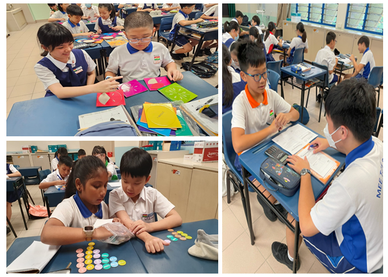 Students in school uniforms work together at desks using colorful paper shapes and coin-like tokens in a classroom.