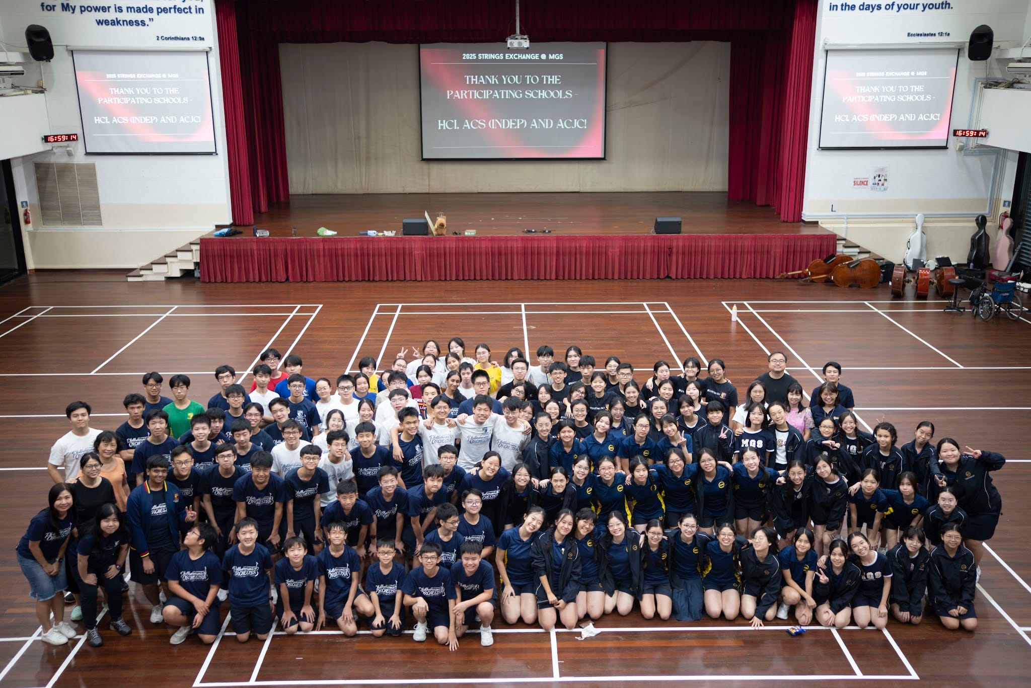 Large group of students posing on a hall floor at the 2025 Strings Exchange event at MGS.