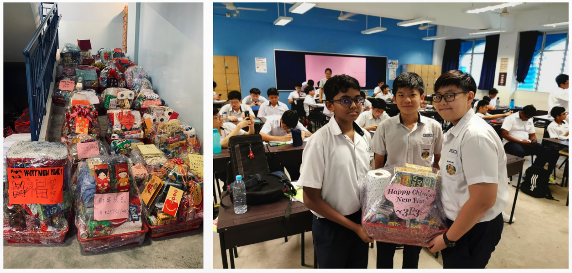 Three school boys hold a Chinese New Year gift basket in a classroom, beside a pile of many wrapped festive hampers.
