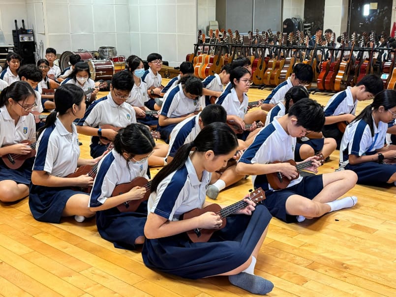 Ngee Ann Secondary students playing ukuleles in a room with a row of guitars at the background.