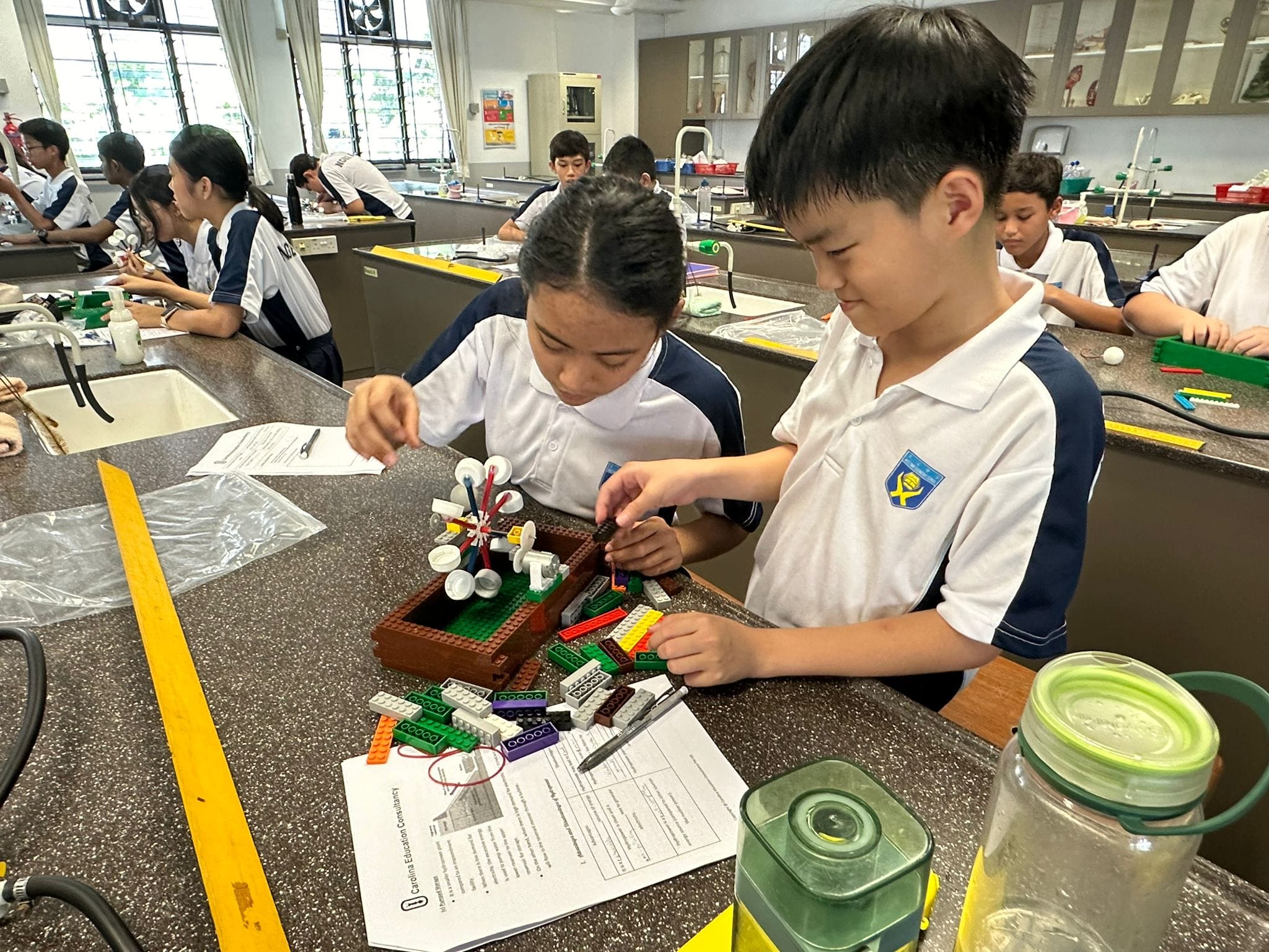 Ngee Ann Secondary students working in pairs to build LEGO models, guided by a worksheet, in the Science Laboratory.