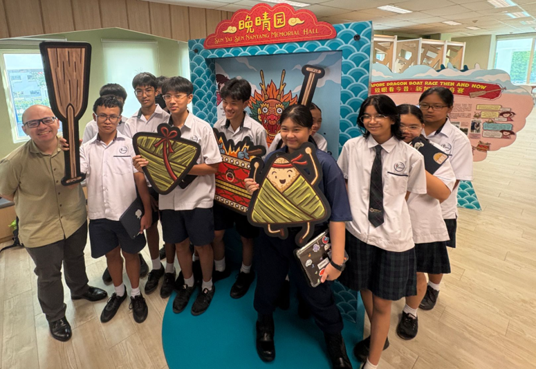 Students in school uniforms pose with decorative rice dumpling props at Sun Yat Sen Nanyang Memorial Hall.