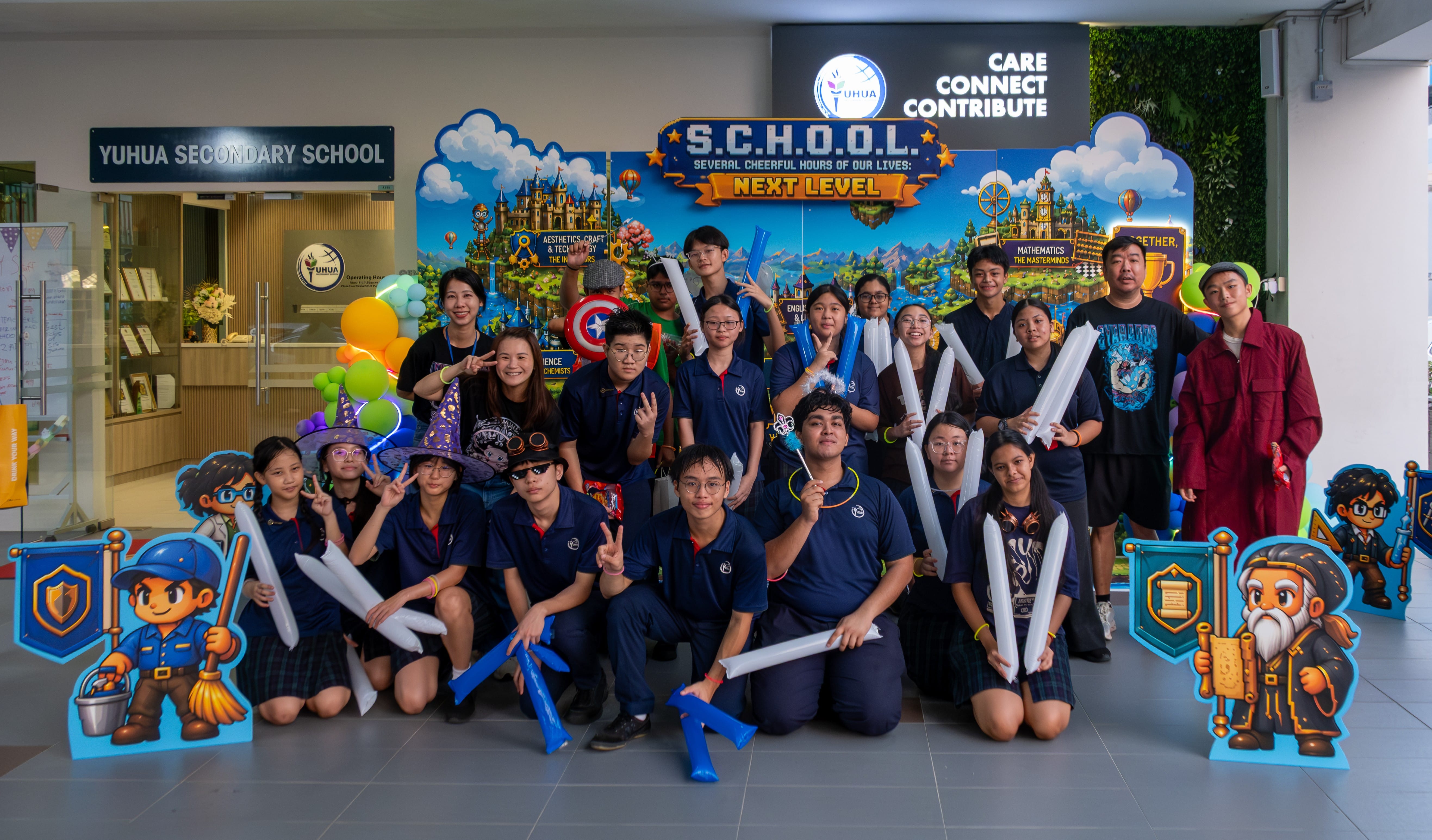 Students in blue uniforms pose before a colorful balloon arch with "Be The Change From Inside Out" signage.