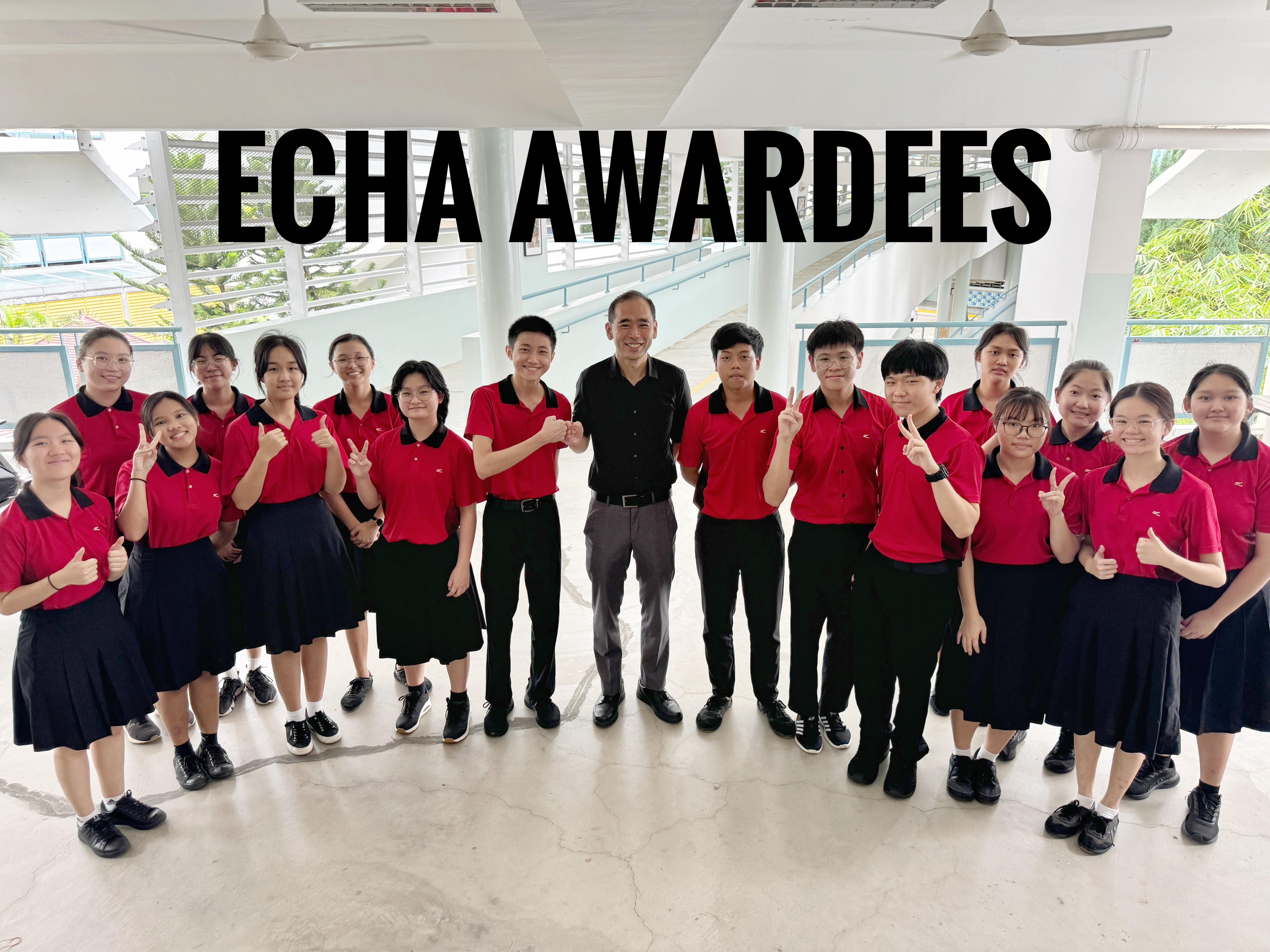 Group of students in red uniforms posing with an adult for an ECHA Awardees photo outdoors.