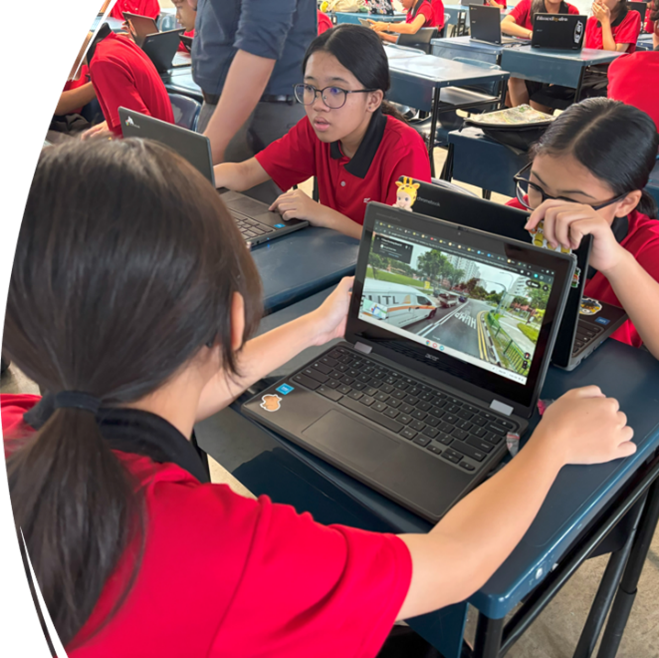 Three students in red uniforms sit at desks, looking at a laptop screen showing a street view map.