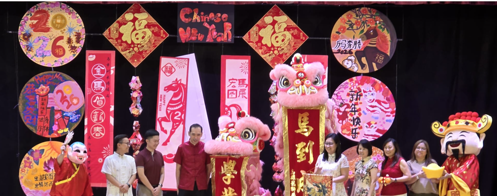 People on stage at a Chinese New Year celebration with lion dance costumes and red festive decorations.