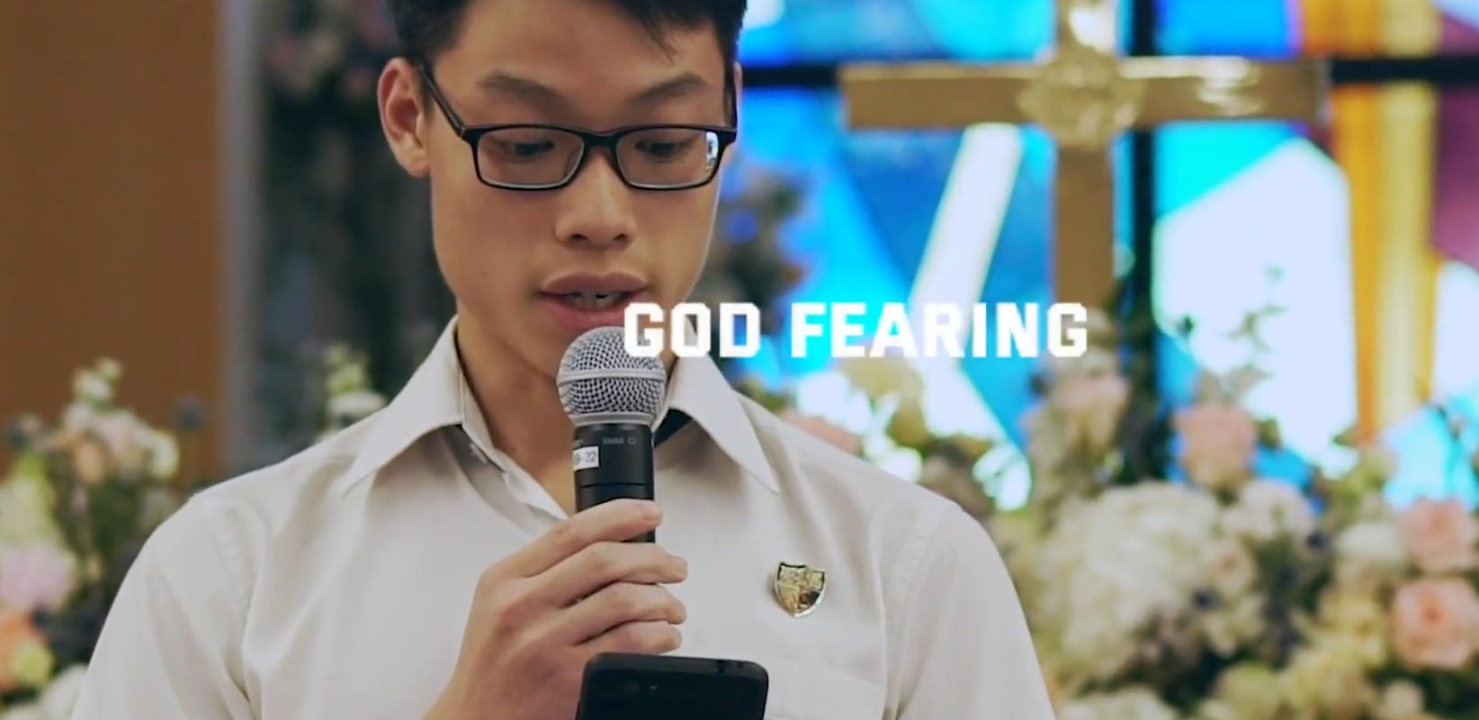 Student speaking into a microphone in a church, with text reading GOD FEARING overlaid.