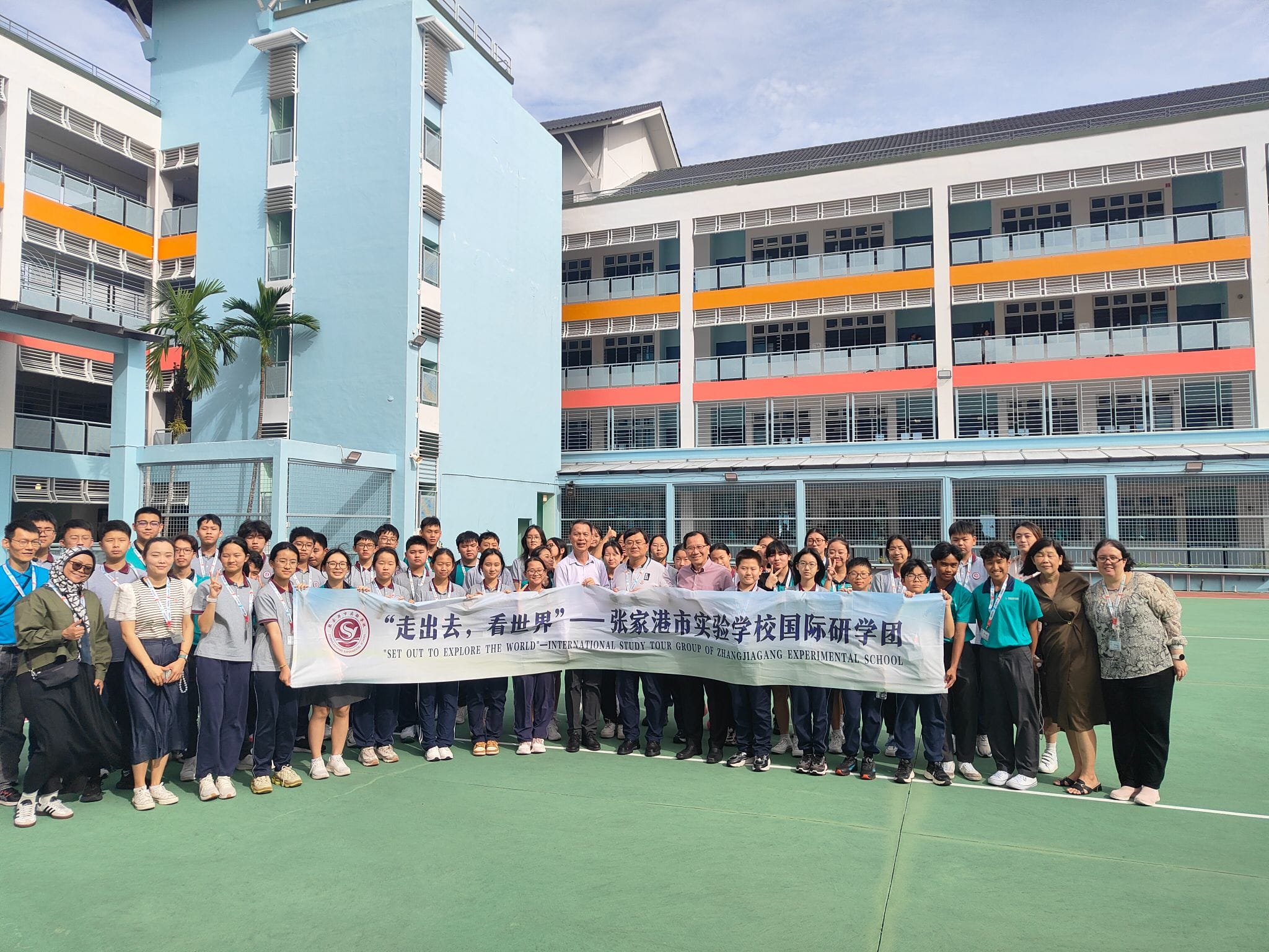 Large group of students and adults posing outdoors holding a banner for Zhangjiagang Experimental School international study tour.