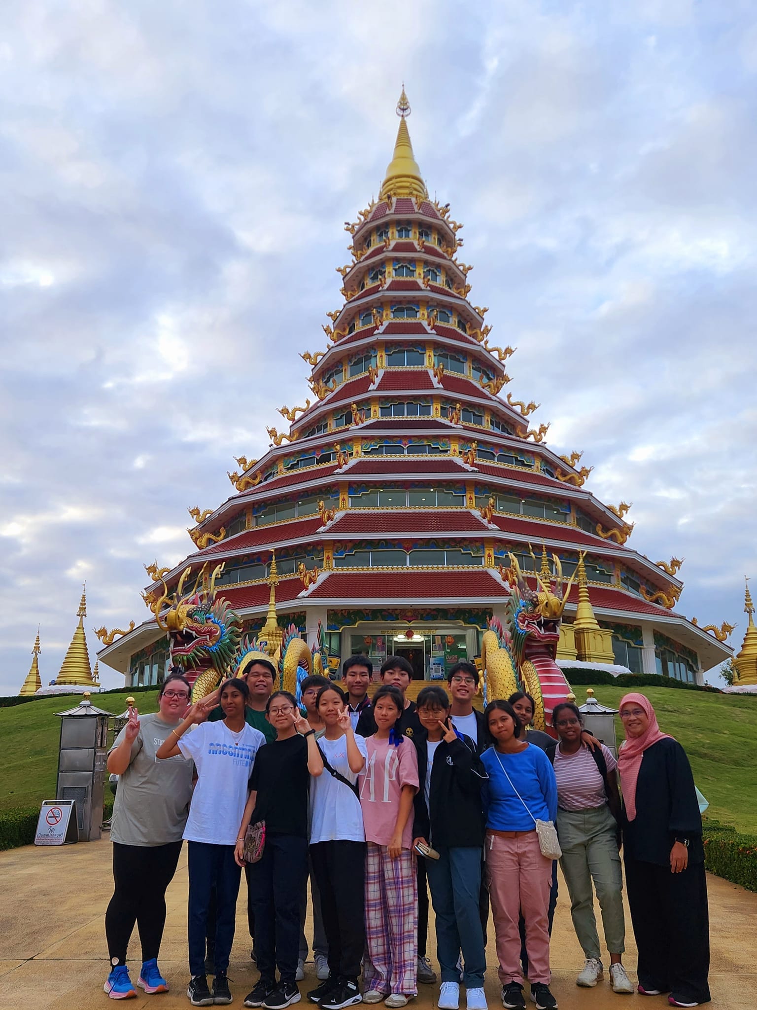 Students standing at the base of a Thai temple pagoda.