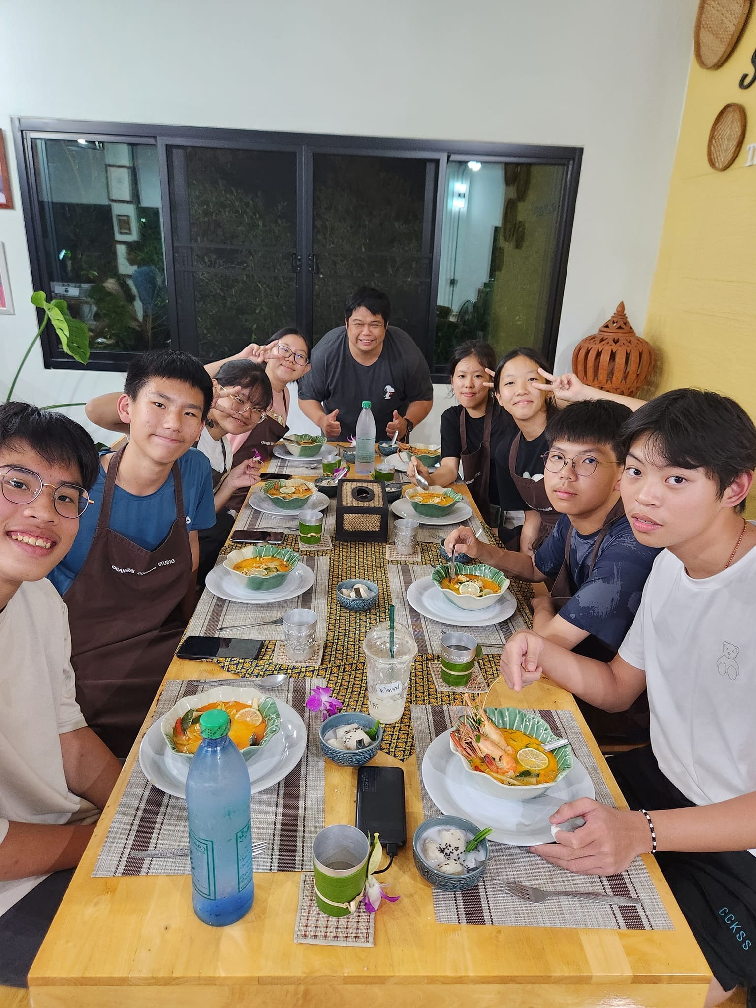 A group of students about to eat a Thai meal at a long table.