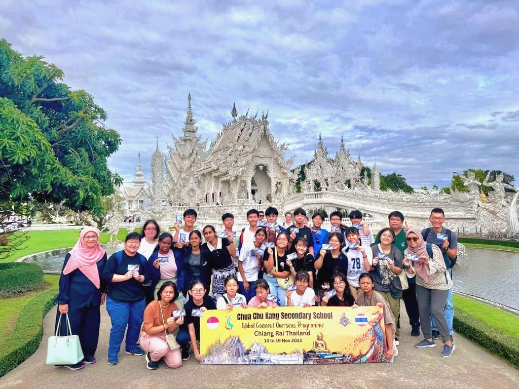 A group of students pose with a banner in front of the White Temple in Chiang Rai, Thailand, November 2023.