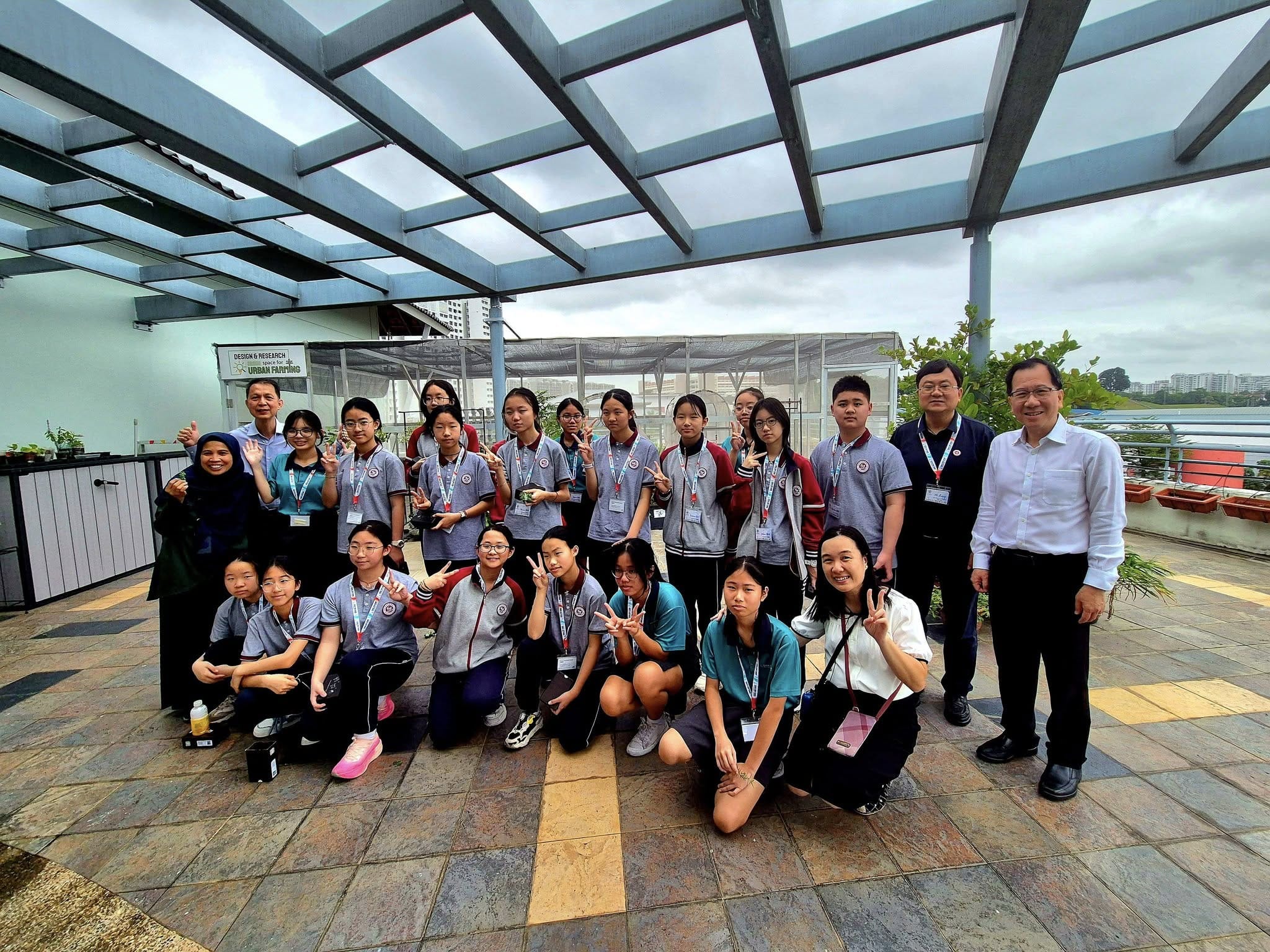 A group of students and some adults take a group photo on a rooftop.