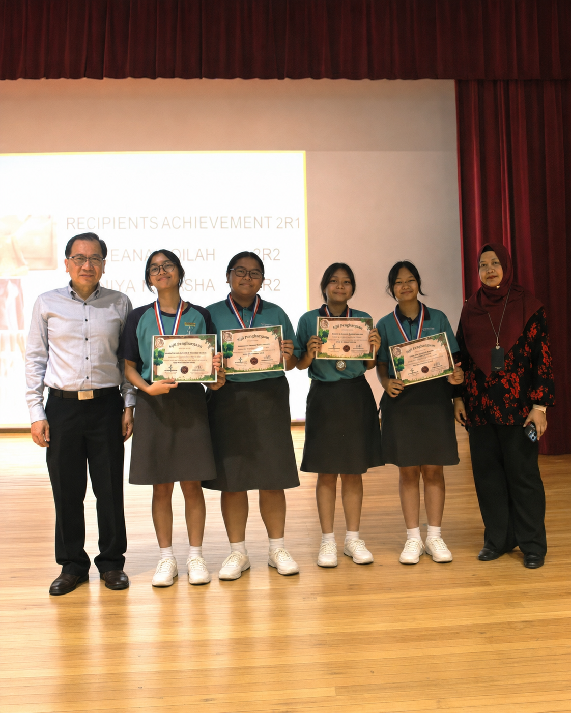Two adults and four students pose for a photograph on stage