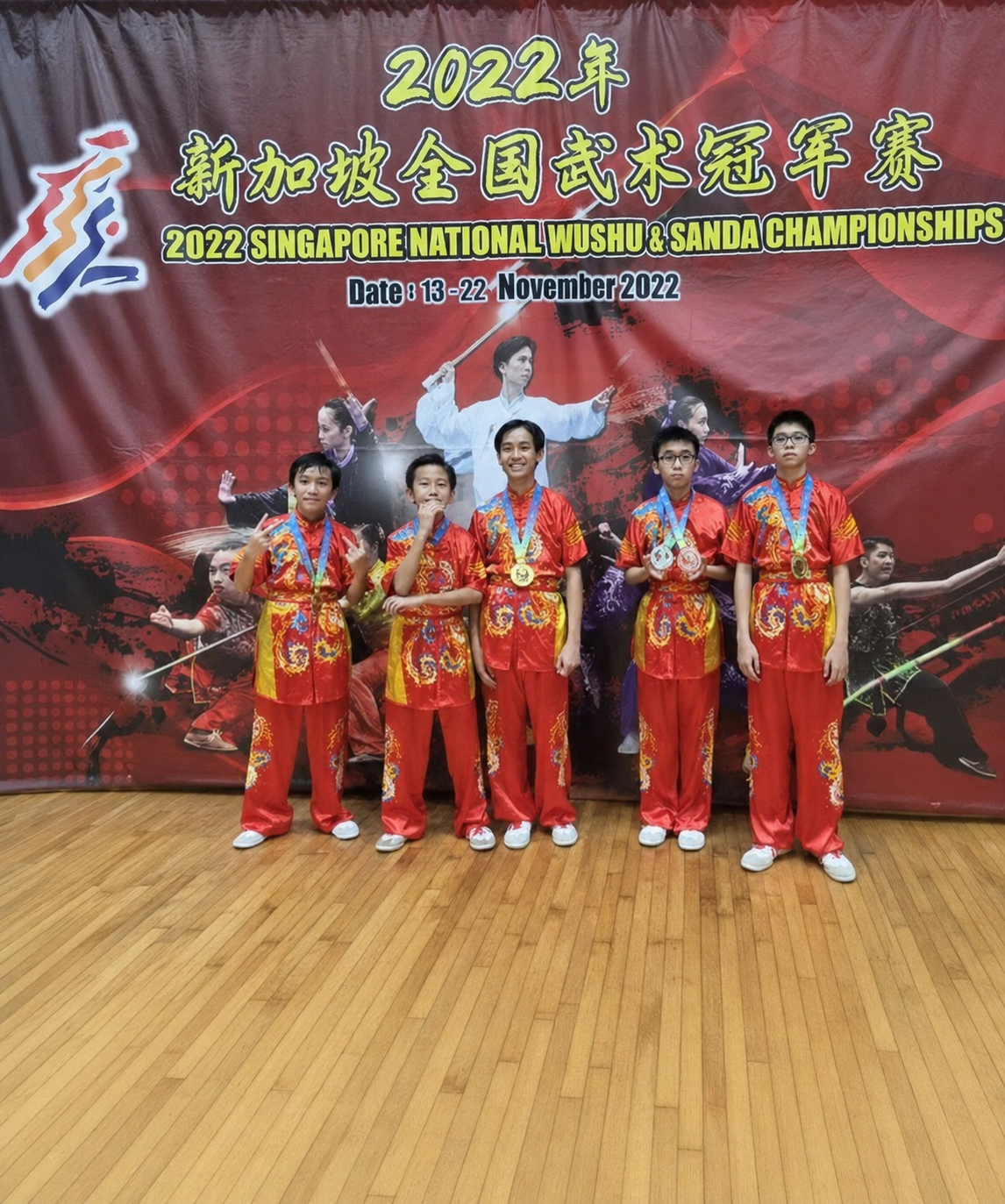 5 boys in red wushu costume holding medals