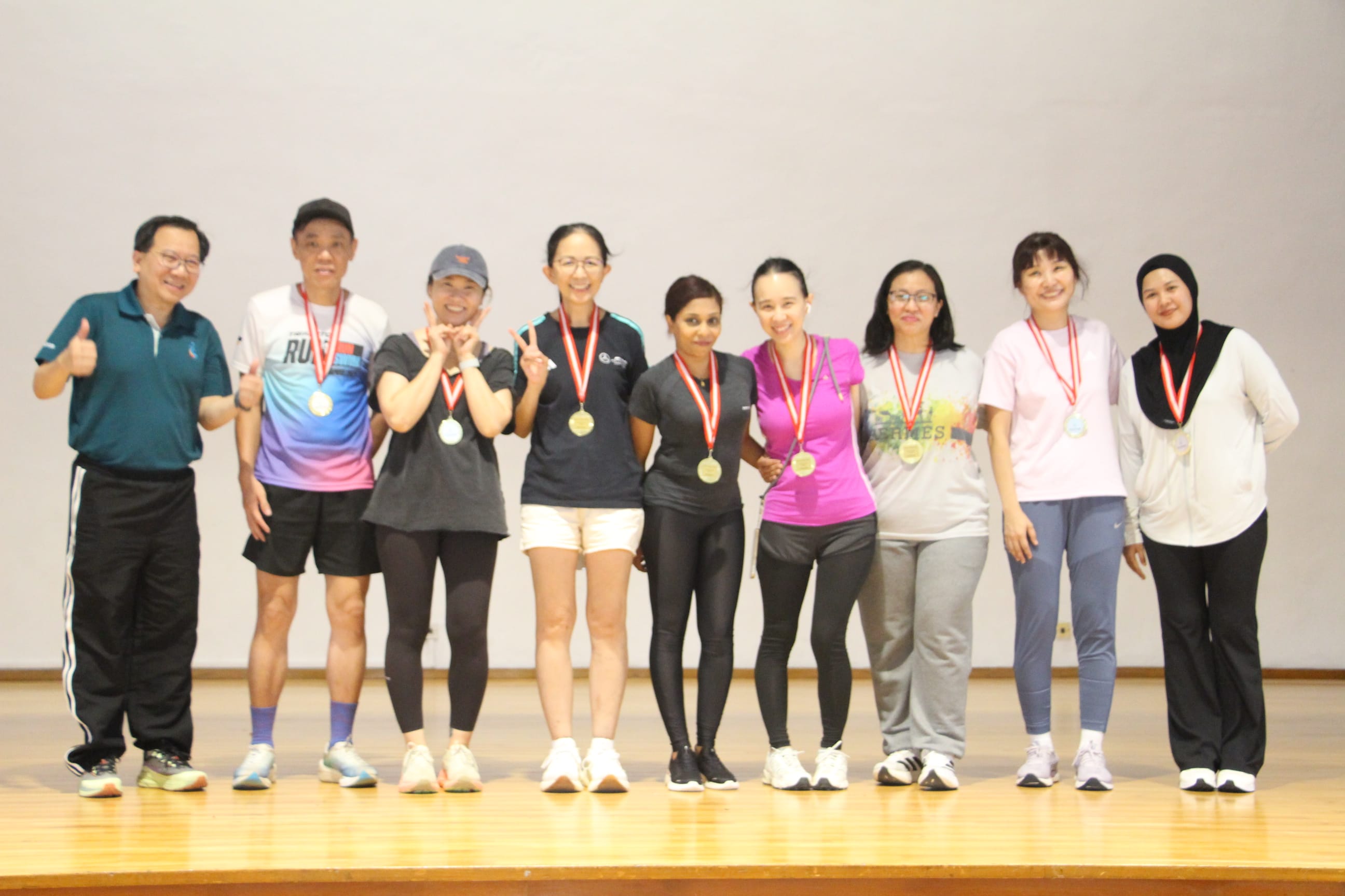 principal and a group of parents pose with their medals on stage