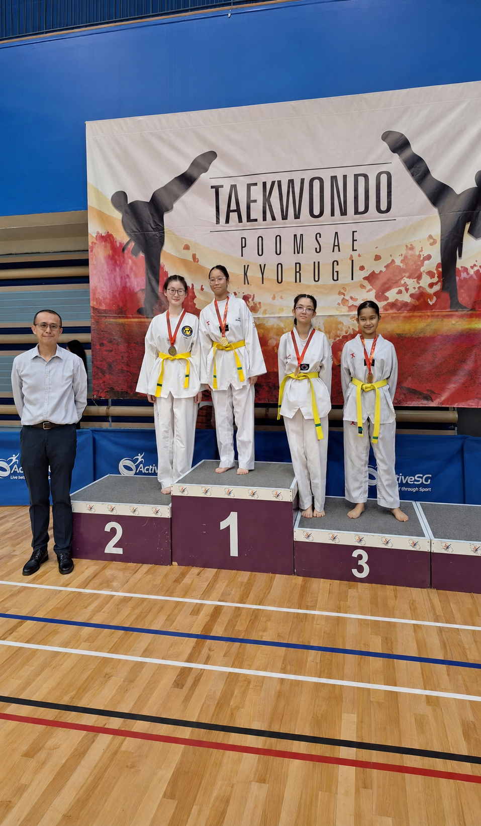 4 girls in taekwondo gi on a podium