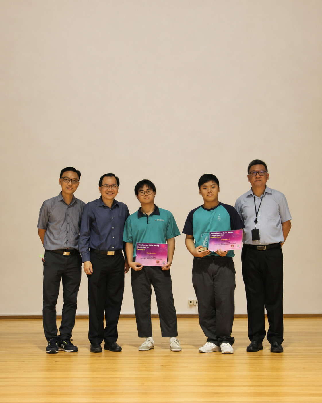2 boys and 3 adults pose on stage