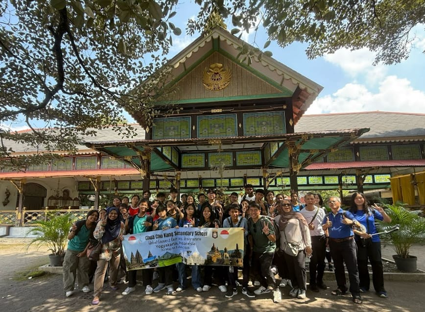 A large student group poses with a Chua Chu Kang Secondary School banner in front of a traditional Javanese building.