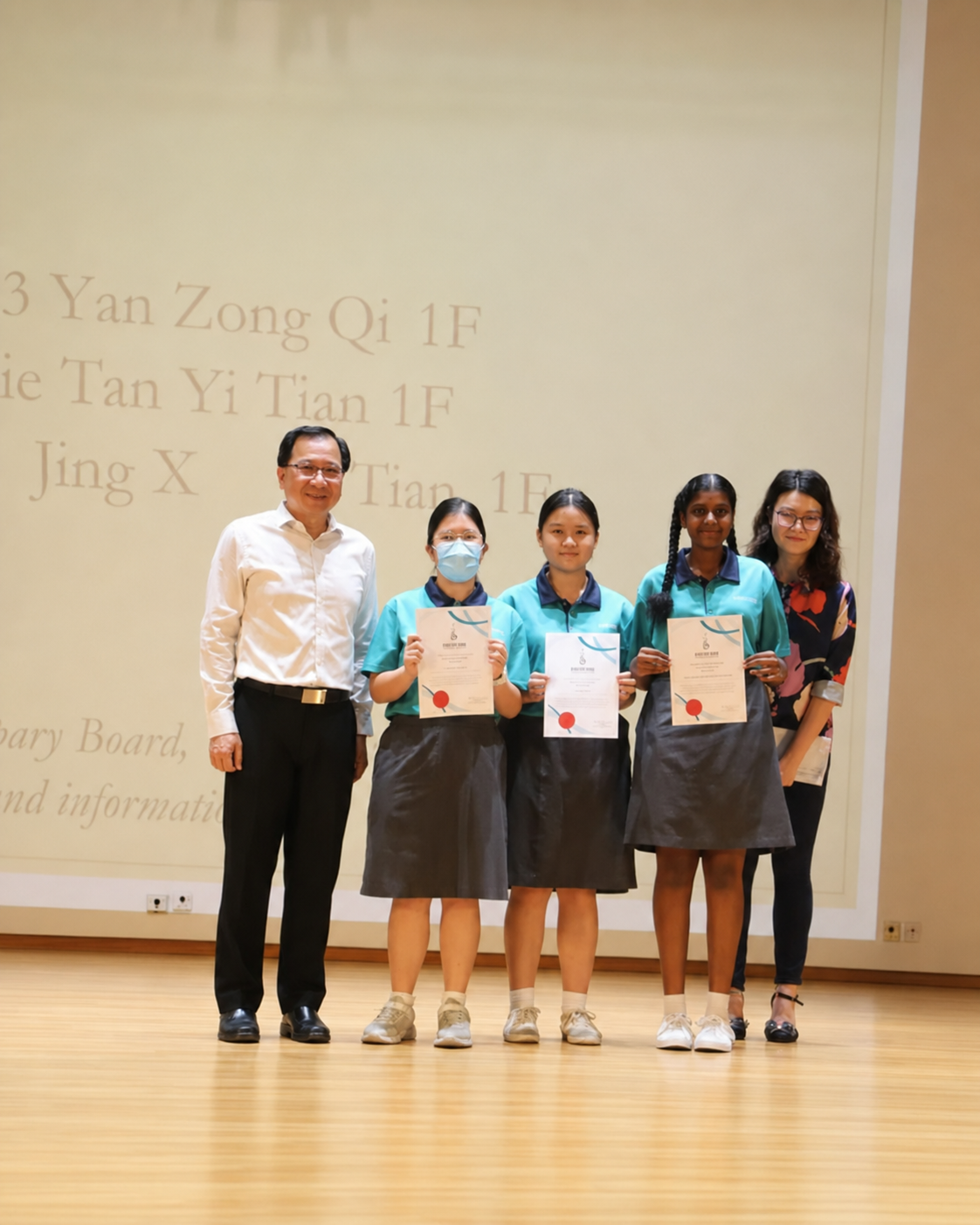 2 adults and 3 students pose on stage