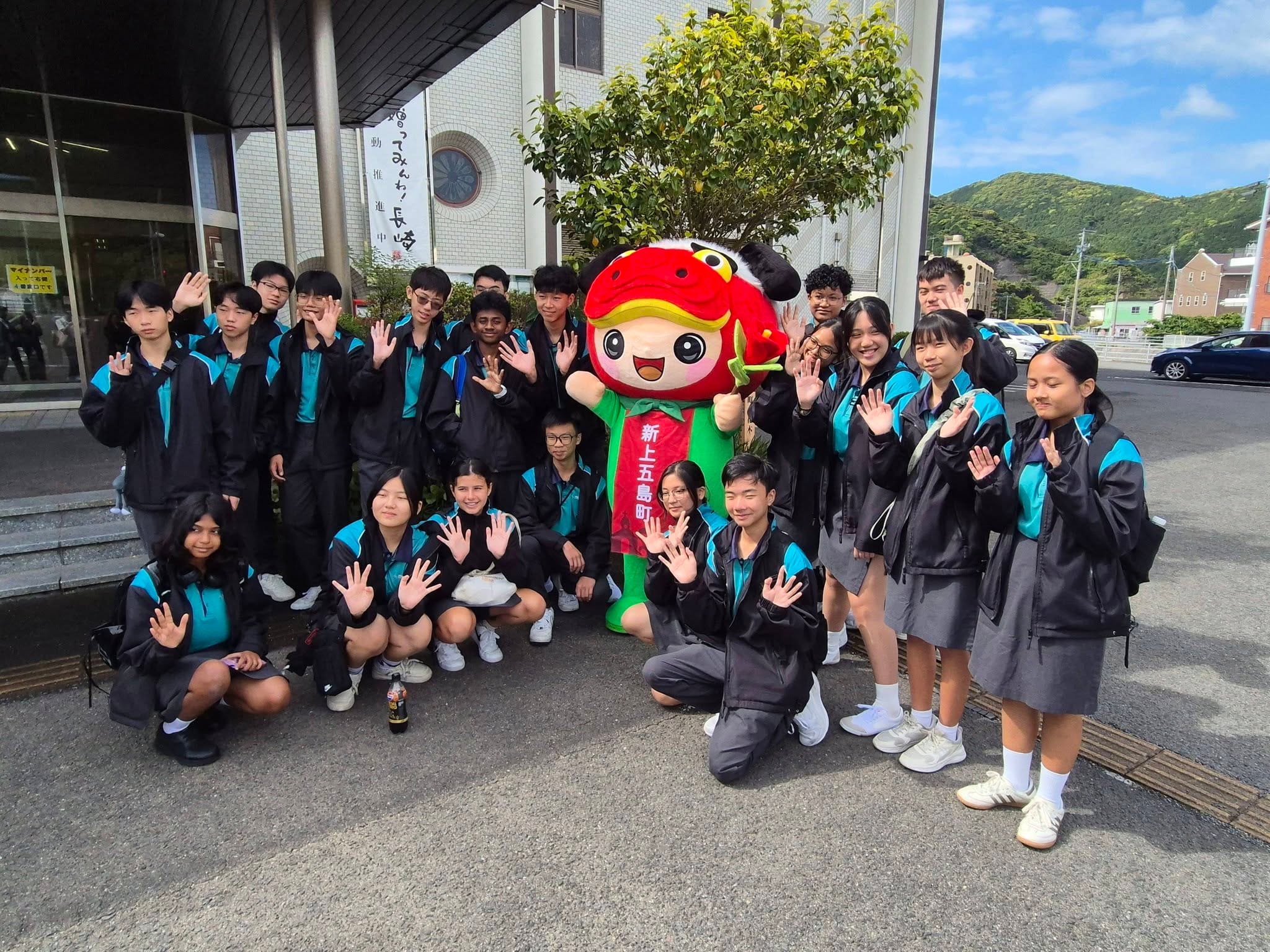 A group of students take a photo with a green and red mascot