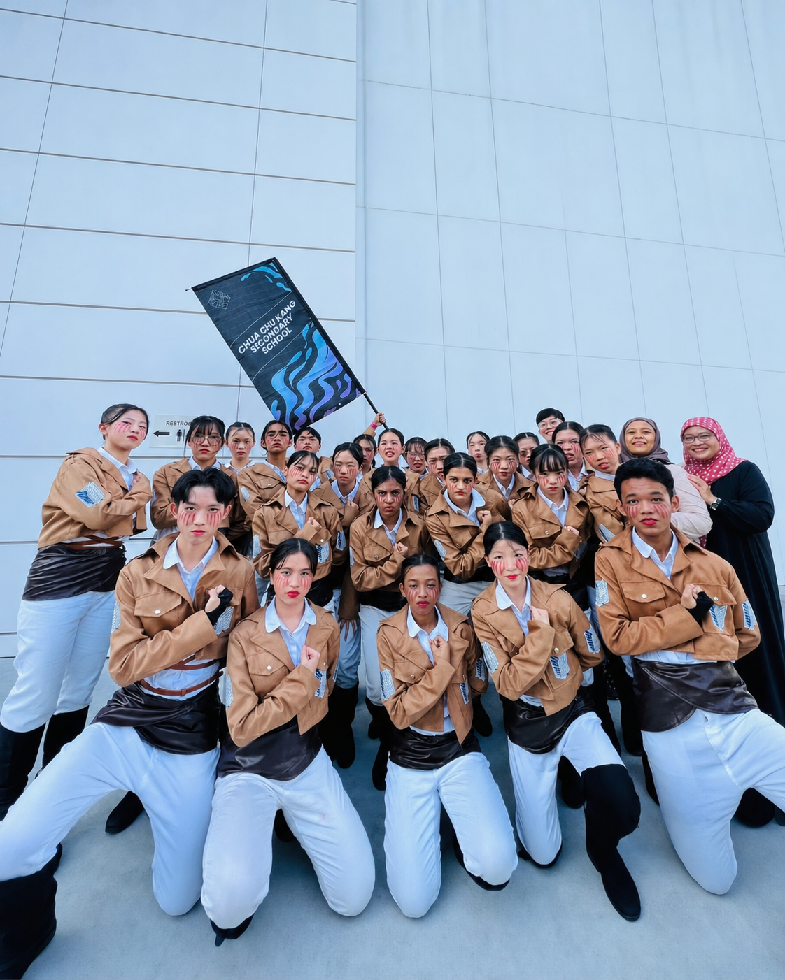 A group of dancers in costume in front of a white building